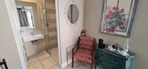 a bathroom with a sink and a chair and a mirror at On the Beach Guesthouse Jeffreys Bay in Jeffreys Bay