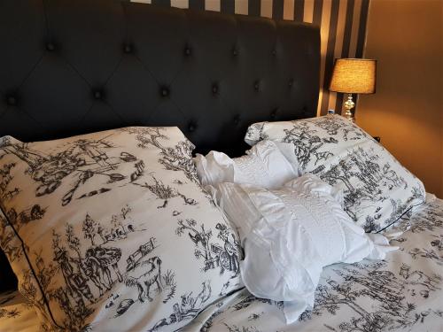 a bed with a black and white comforter and pillows at Le Bon'Aparte - Hypercentre de Fontainebleau in Fontainebleau