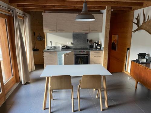 kuchnia z białym stołem i 2 krzesłami w obiekcie Chalet Moose w mieście Morzine