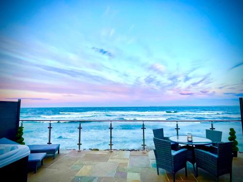 uitzicht op de oceaan met een tafel en stoelen bij 3 Sinclair Bay Lodges in Keiss