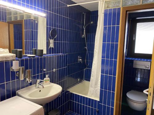 a blue tiled bathroom with a sink and a toilet at Ferienwohnung am Marktplatz in Weinheim