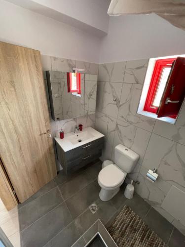 een badkamer met een toilet, een wastafel en een spiegel bij Sugar Stone House 2 in Pirgos Dhirou