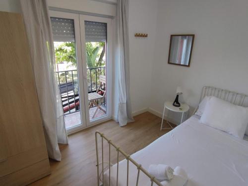 1 dormitorio con 1 cama y puerta a un balcón en Almona junto al río - Kainga Homes, en Sevilla