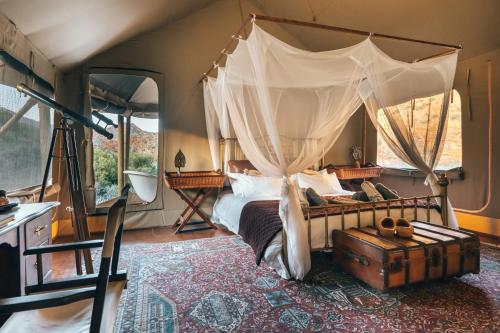 a bedroom with a canopy bed with a suitcase at Wolwehoek Private Reserve in Montagu