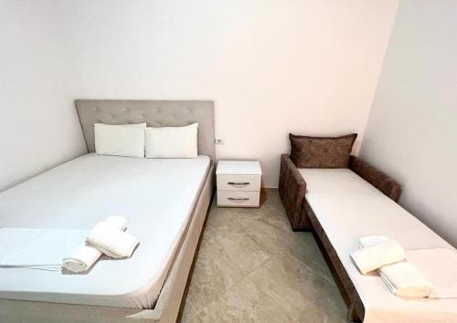 2 bedden in een kleine kamer met witte lakens bij Guesthouse Siars in Ksamil
