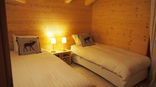 - 2 lits dans une chambre en bois avec 2 lampes dans l'établissement Résid. Les Esserts A42, à Champoussin