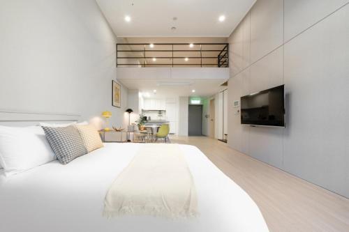 a large white bedroom with a large bed and a television at Le Collective Yeosu in Yeosu