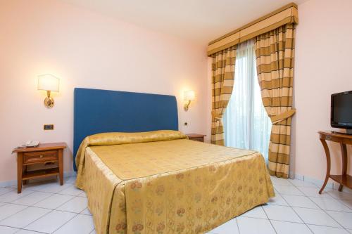 a bedroom with a bed with a blue headboard and a television at Hotel Villa Albani in Nocera Superiore