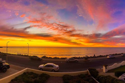 a sunset with cars on a road near the ocean at Beach apartment 10/22 esplanade sea-views in Glenelg