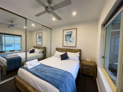 a bedroom with two beds and a ceiling fan at Beach apartment 10/22 esplanade sea-views in Glenelg