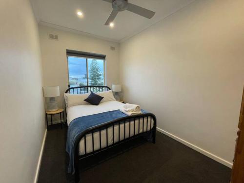 a bedroom with a bed with a ceiling fan at Beach apartment 10/22 esplanade sea-views in Glenelg