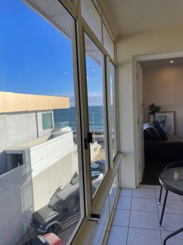 a room with a balcony with a view of a car at Beach apartment 10/22 esplanade sea-views in Glenelg