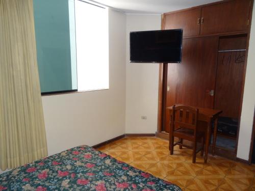 una camera con letto, scrivania e TV di Hotel Nova a Lima