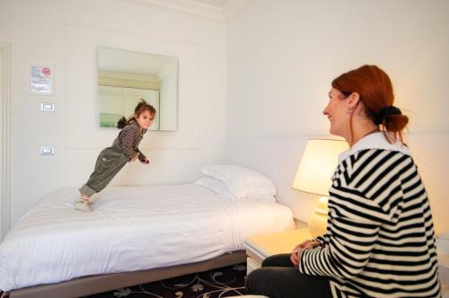 a little girl jumping on a bed in a hotel room at Etrusco Arezzo Hotel - Sure Hotel Collection by Best Western in Arezzo
