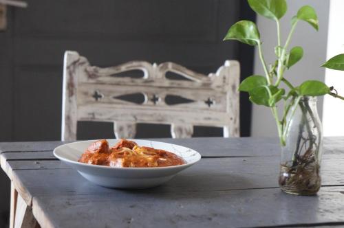 a bowl of food on a table with a chair at Bed & Chai Guesthouse in New Delhi