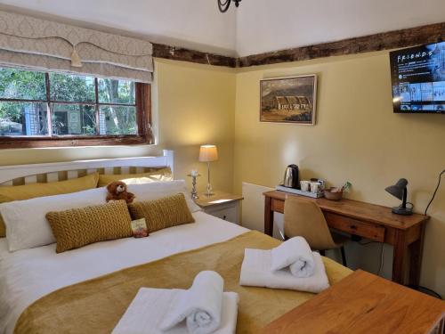 a bedroom with a bed and a desk with towels at Schuilhoek Garden Terraces in Cape Town