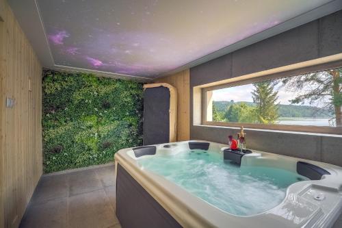 a bath tub in a room with a large window at Znamirowickachata SAUNA JACUZZI SPA in Znamirowice