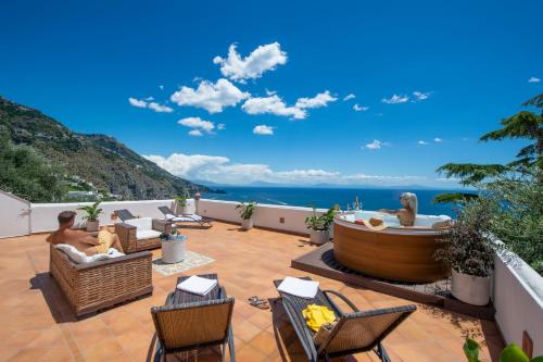a patio with a hot tub and chairs at Villa Algarrobos in Praiano