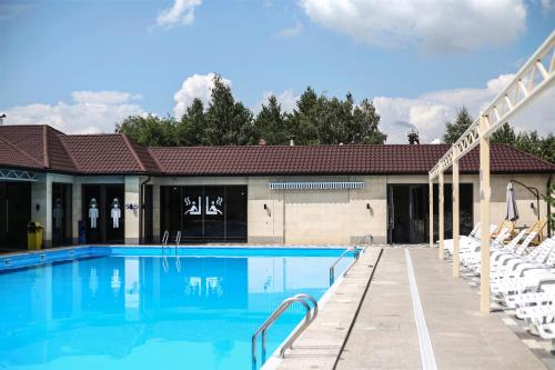 a swimming pool with white chairs next to a building at Dvin Hotel in Pavlodar