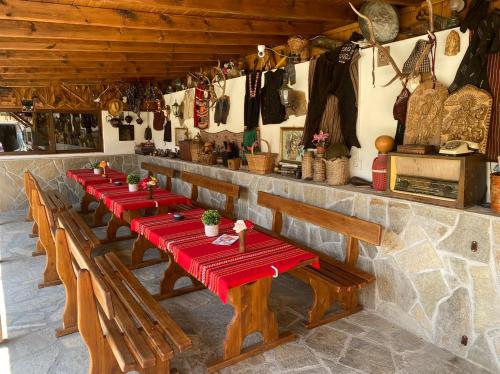 une rangée de tables en bois dans un restaurant avec des goulottes rouges dans l'établissement Chilingirovata Kashta, à Pavel Banya