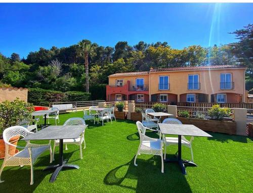 eine Gruppe von Tischen und Stühlen auf einem Rasen in der Unterkunft Hotel Le Bon Port in Collioure