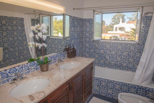een blauwe en witte badkamer met 2 wastafels en een bad bij CASA SACHA in Carvoeiro