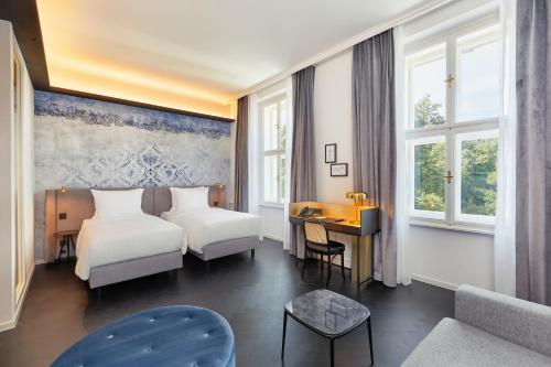 a hotel room with two beds and a desk at Hyperion Hotel Salzburg in Salzburg
