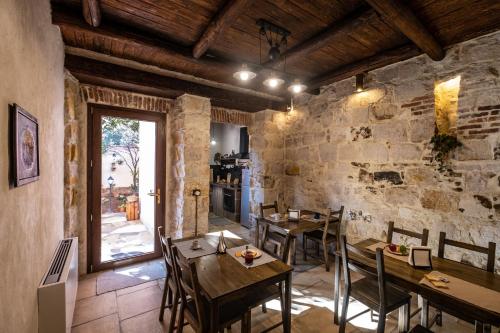 een eetkamer met tafels en stoelen en een stenen muur bij Il Rifugio dei Minatori in Iglesias