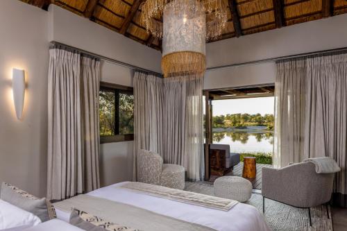 sypialnia z 2 łóżkami i dużym oknem w obiekcie Simbavati Waterside w mieście Klaserie Private Nature Reserve