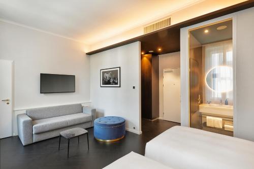 a room with a bed and a couch and a tv at HYPERION Hotel Salzburg in Salzburg