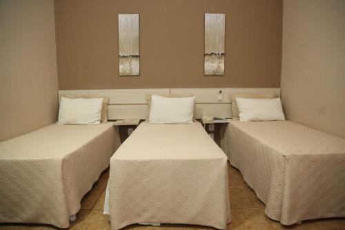een kamer met 2 bedden en 2 tafels bij Hotel Mirage in Vilhena
