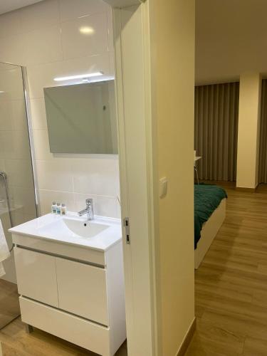 a bathroom with a sink and a mirror and a bed at Quinta da Menina Guest House in Vila Real