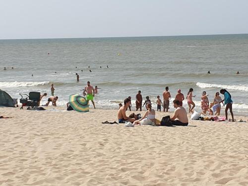 un groupe de personnes assises sur la plage dans l'établissement Apartment Raversijde with Seaview, à Ostende