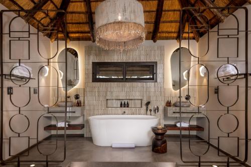 ein Badezimmer mit einer großen Badewanne und einem Kronleuchter in der Unterkunft Simbavati Waterside in Klaserie Private Nature Reserve