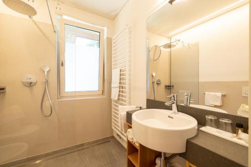 a white bathroom with a sink and a shower at Hotel Gartenresidence Zea Curtis in Merano