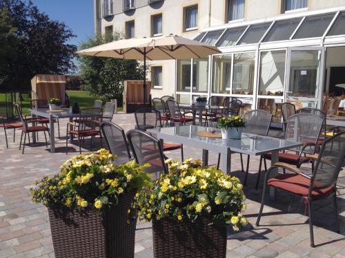 a patio area with chairs, tables and umbrellas at Hotel Am Quellberg in Recklinghausen