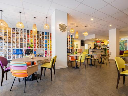 een restaurant met kleurrijke stoelen en tafels en een cafetaria bij ibis Styles Perpignan Centre Gare in Perpignan