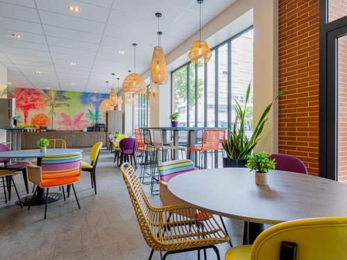 - une salle à manger avec des tables, des chaises et des fenêtres dans l'établissement ibis Styles Perpignan Centre Gare, à Perpignan