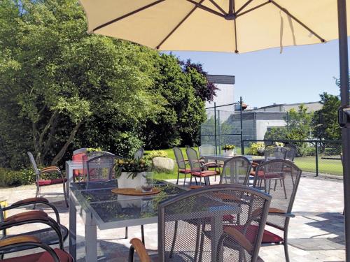 a patio with tables and chairs and an umbrella at Hotel Am Quellberg in Recklinghausen