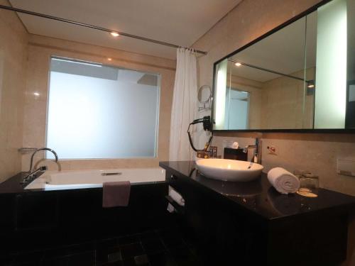 a bathroom with a tub and a sink and a mirror at Novotel Balikpapan in Balikpapan