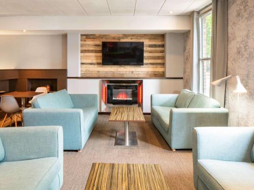 a living room with two blue couches and a fireplace at ibis York Centre in York