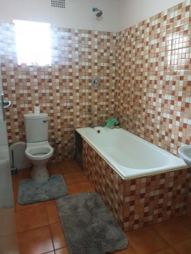 a bathroom with a tub and a toilet and a sink at House of Joy in Lilongwe