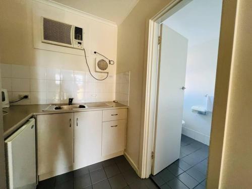 a small kitchen with a sink and a microwave at 1BR at Moseley st Glenelg 30 in Glenelg