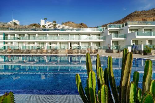 a hotel with a swimming pool and cactus at Morasol Suites in Puerto Rico de Gran Canaria