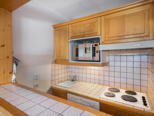 a kitchen with a stove and a microwave at Appartement Courchevel 1650, 2 pièces, 4 personnes - FR-1-563-82 in Courchevel