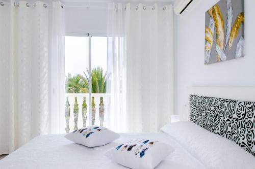 ein weißes Bett mit zwei Kissen und einem Fenster in der Unterkunft Espanatour MADONNA in Torrevieja