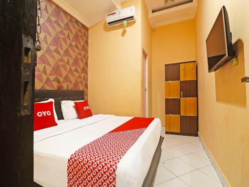 a bedroom with a bed with red pillows and a tv at OYO 90492 Papi Inn Guesthouse in Palangkaraya