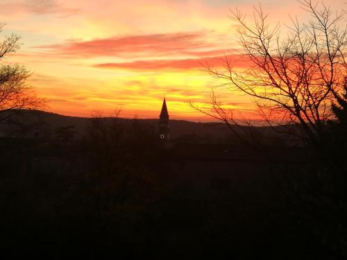 a sunset with a clock tower in the distance at Krasberry Ježev brlog in Komen