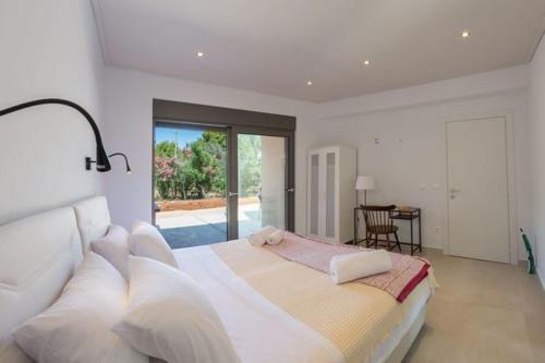 a white bedroom with a large bed with white pillows at Eucalyptus -- Agios Ioannis Beachfront Apartment in Lefkada Town