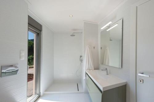 a white bathroom with a shower and a sink at Eucalyptus -- Agios Ioannis Beachfront Apartment in Lefkada Town